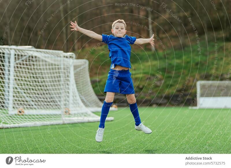 Junger Fußballspieler beim Feiern auf dem Spielfeld Sport Freude jung Spieler springen Uniform Feld im Freien Tor Netz Waffen gedehnt Gras grün blau Bausatz