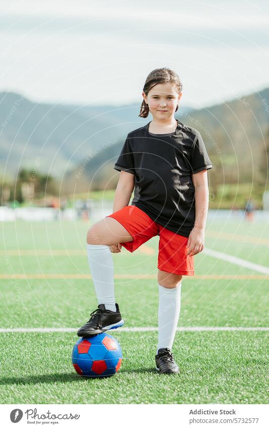 Junges Mädchen posiert mit Fußball auf dem Feld Ball Sport Natur Selbstvertrauen Pose ruhen farbenfroh Kleidung im Freien jung Athlet sportlich lässig Freizeit