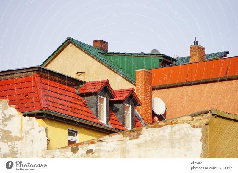 eng aneinander gebaute Wohnhäuser mit Abbruchwand, rot und grün gedeckten Ziegeldächern, Schornsteinen, Satellitenschüsseln, Dachgauben, Fenstern, Dachterrassen