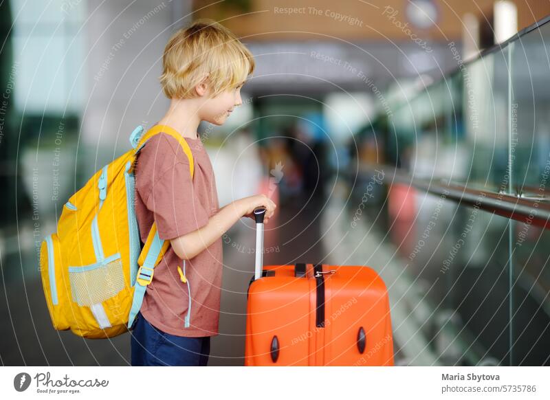 Niedlicher Junge im Teenageralter auf einem internationalen Flughafen oder auf dem Bahnsteig. Einchecken. Reisen, Tourismus, Urlaub für Familie mit Kindern Konzept
