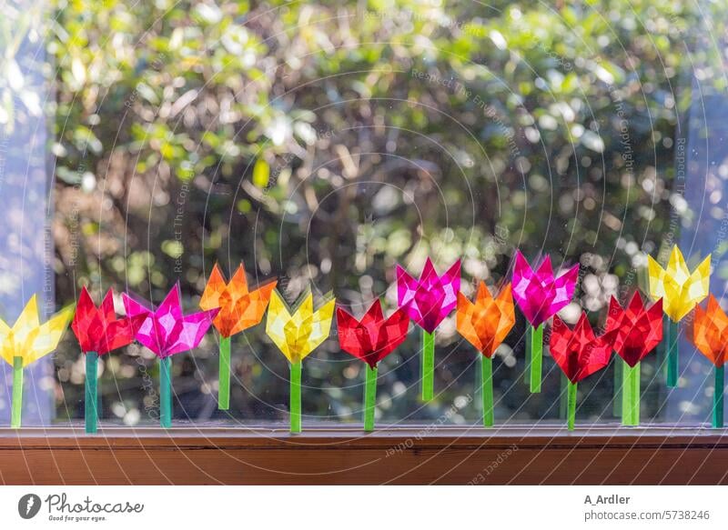 gefaltete bunte Blumen aus Transparentpapier kleben am Fenster abstrakt gebastelt traditionell Farbe geschnittenes Papier Dekor handgefertigt kreativ diy Hobby