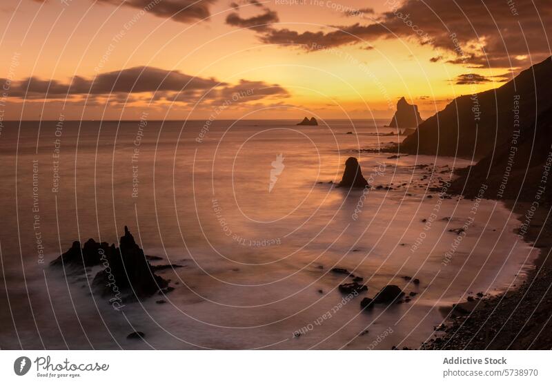 Das letzte Licht des Tages taucht Playa de Benijo in ein sanftes, bernsteinfarbenes Licht, das die einzigartigen Felsformationen und das ruhige Meer hervorhebt.