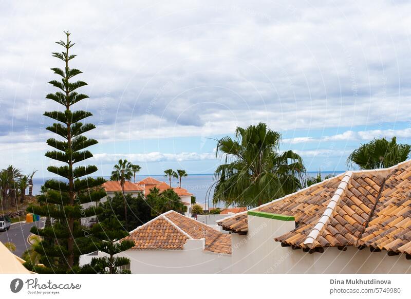 Blick auf Teneriffa. Rote Dachziegel und grüne Bäume und Palmen mit Meer Luftaufnahme mit bewölktem Himmel. Insel Dachterrasse Antenne Kacheln rote Dachziegel