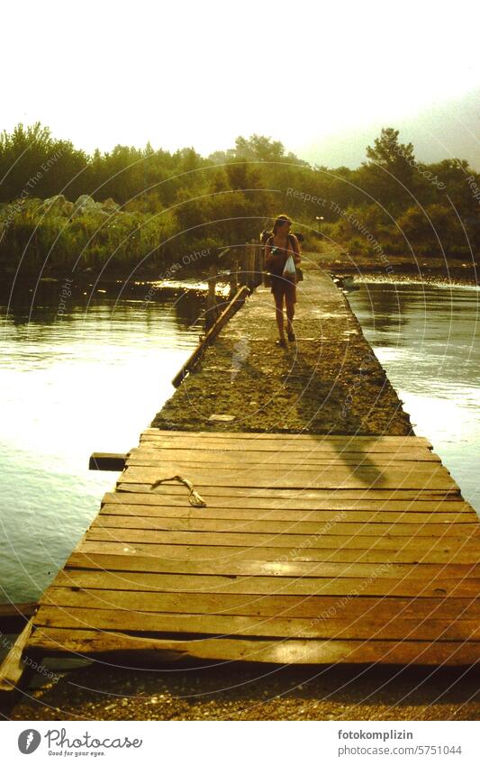 Frau wandert auf einem Holzsteg wandern Fluss exotisch Steg Brücke schwül Abendstimmung Sommer Reise Weltenbummler Urlaub pilgern Pilgerin Ferien holzsteg