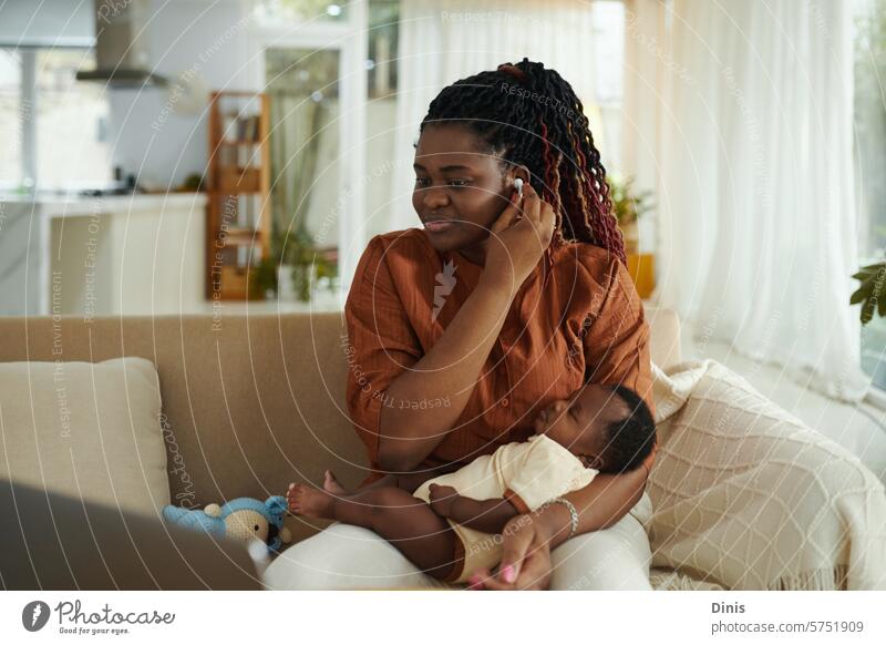 Black woman using earbuds to watch educational video when her baby is sleeping learn study mother kid motherhood happy rocking child care parenthood maternity