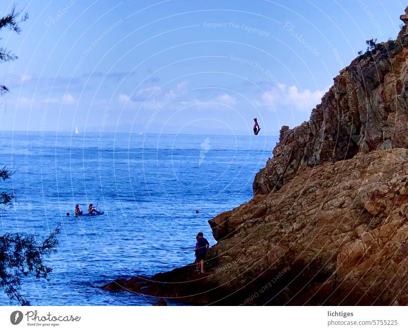 Springender Punkt- junge springt aus großer Höhe von einem Felsen ins Meer meer sprung stunt mut klippensprung waghalsig