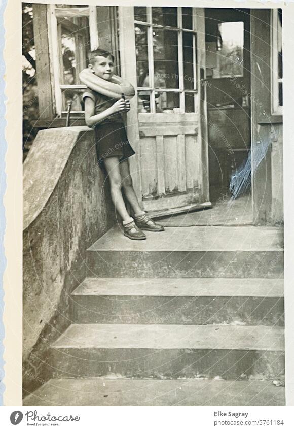 Analog - Junge mit Schwimmreifen auf einer Treppe- altes Kinderfoto Nostalgie Erinnerung Porträt Blick Schwarzweißfoto sentimental Fotografie Familienalbum