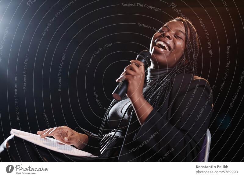 Porträt einer schwarzen Frau, die auf der Bühne lacht und ein Mikrofon hält, während sie in einer Comedy-Show auftritt aufstehen Komödie Talkshow Comic Komiker
