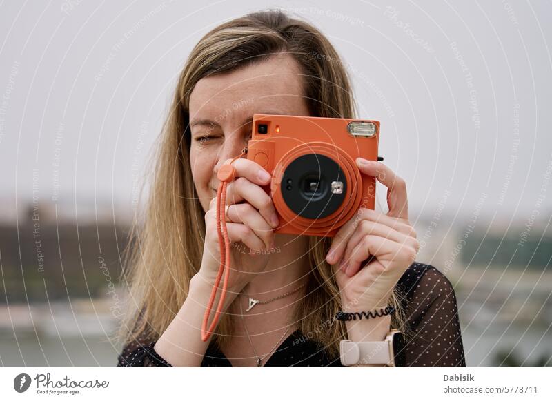 Weiblicher Reisender, der ein Bild mit einer alten Sofortbildkamera aufnimmt Tourist sofort Fotokamera Frau Tourismus Fotografie altehrwürdig Erinnerungen