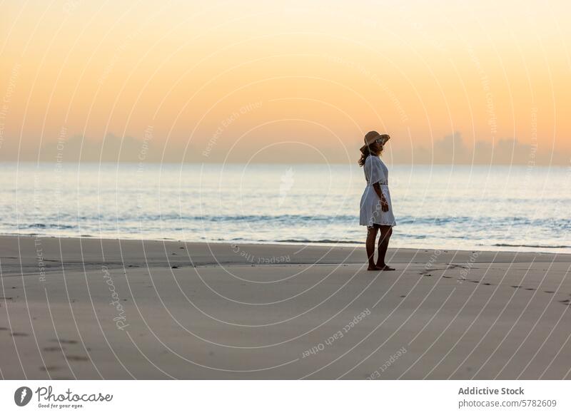 Gelassener Moment einer Frau am Strand in der Morgendämmerung Sonnenaufgang Natur Gelassenheit Erholung Meer Sand ruhig Einsamkeit weißes Kleid Strohhut