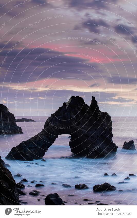 Dämmerung über dem ruhigen Meer mit natürlichem Felsbogen Meereslandschaft Gelassenheit violetter Himmel Steine Abenddämmerung Küstenlinie Landschaft Wasser