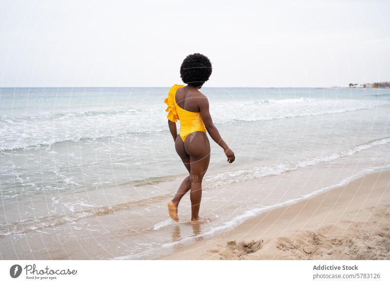 Frau im gelben Badeanzug beim Spaziergang am Strand Ein-Schulter- Afrikanisch Freizeit Meeresufer winken Sand Wasser MEER Urlaub Sommer reisen Küstenlinie Ufer