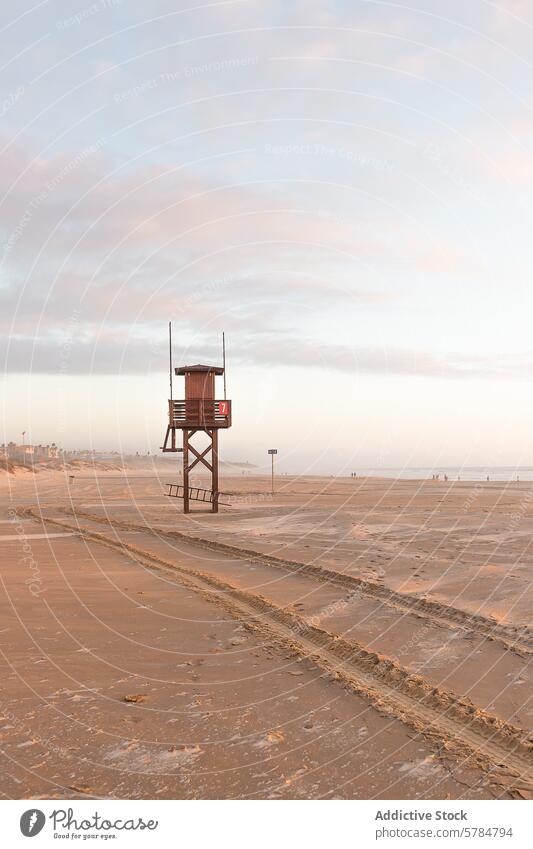 Gelassene Strandszene mit leerem Rettungsschwimmerturm in der Abenddämmerung Rettungsschwimmturm ruhig Sand pastellfarbener Himmel Gelassenheit Nebensaison
