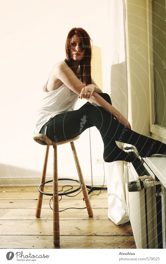 Junge Frau sitzt auf einem Hocker an der Heizung Jugendliche Arme Beine 18-30 Jahre Erwachsene Hemd Strumpfhose rothaarig langhaarig Dielenboden Fenster Blick