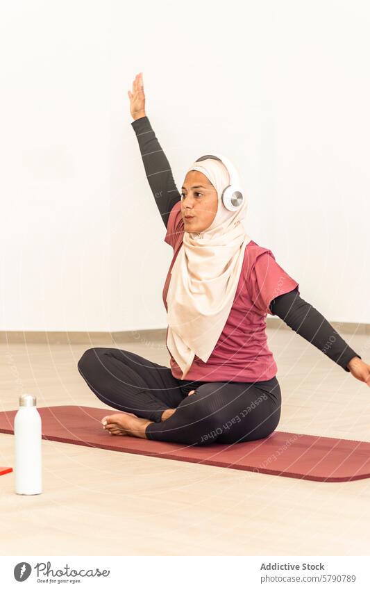 Muslimische Frau übt Yoga in bequemer Kleidung muslimisch Pose ardha matsyendrasana sitzend verdrehen Hijab Sportbekleidung Wellness Gesundheit Übung Ruhe