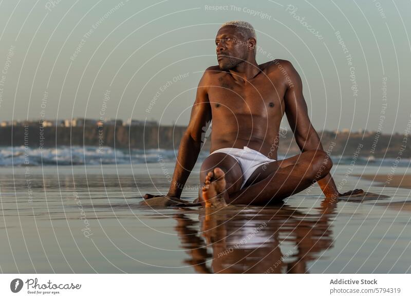 Nachdenklicher afroamerikanischer Mann sitzt bei Sonnenuntergang am Strand Model Afroamerikaner schwarz Sitzen Reflexion & Spiegelung ruhig Ufer Ethnizität