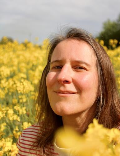 eine lächelnde Frau im Rapsfeld raps rapsfeld landwirtschaft ökologische landwirtschaft gelb anbau pflanzen Nutzpflanze Rapsblüte Frühling Natur Blüte frau