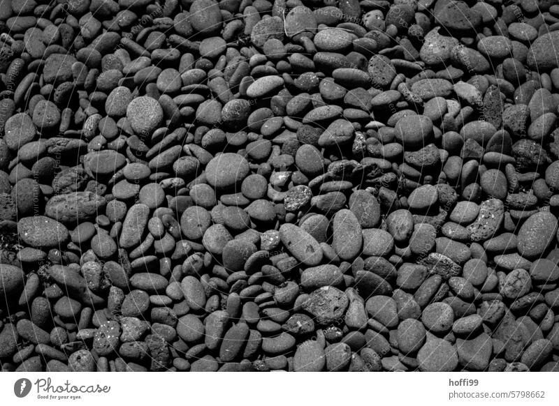 viele schwarze rund geschliffene flache Steine am Strand von Lanzarote Schwarze grau Kieselsteine Steinstrand abstrakt minimalistisch geschliffenes Glas