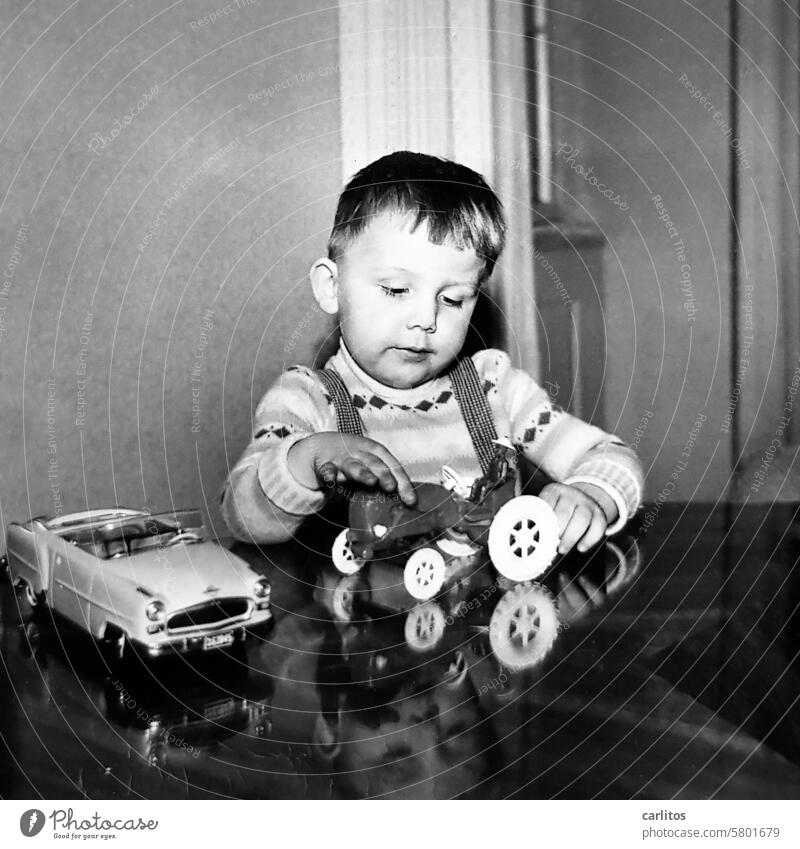 Der kleine carl und sein Lieblingsspielzeug Junge 50er Jahre 60er Jahre Spielzeug Auto Traktor glücklich spielen Schwarzweißfoto Spiegelung retro Stil Cabrio