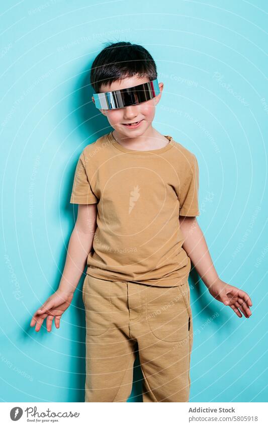 Junge mit futuristischer Sonnenbrille posiert auf türkisem Hintergrund lässig Outfit Bräune posierend reflektierend Lächeln Freude pulsierend Mode Stil modern