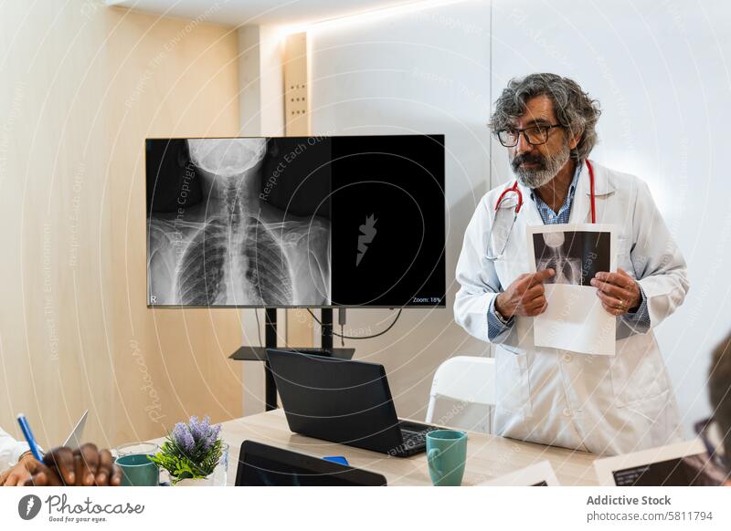 Oberarzt bespricht Röntgenbild mit Kollegen im Krankenhaus Arzt diskutieren Sanitäter Mitarbeiterin Bild professionell Klinik Arbeit medizinisch Büro Senior