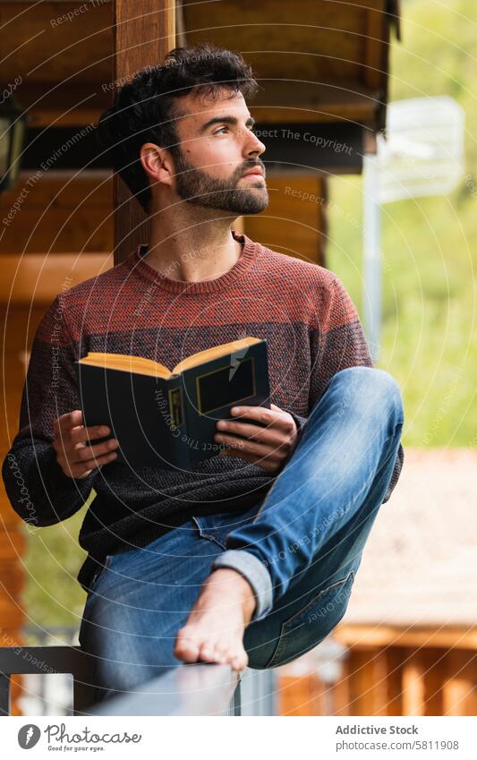 Nachdenklicher Mann auf Terrasse mit Buch lesen nachdenken nachdenklich Urlaub Haus Veranda Literatur männlich Pyrenäen ruhen sich[Akk] entspannen hölzern Kälte