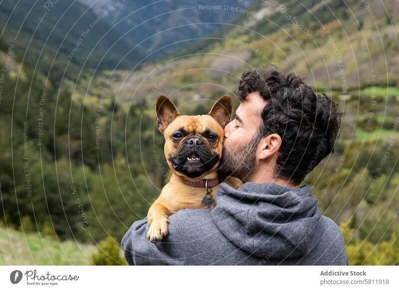 Glücklich reisender Mann küsst süßen Hund im Hochland Berge u. Gebirge Kuss Zusammensein Umarmen Reisender Wanderer männlich Pyrenäen französische Bulldogge