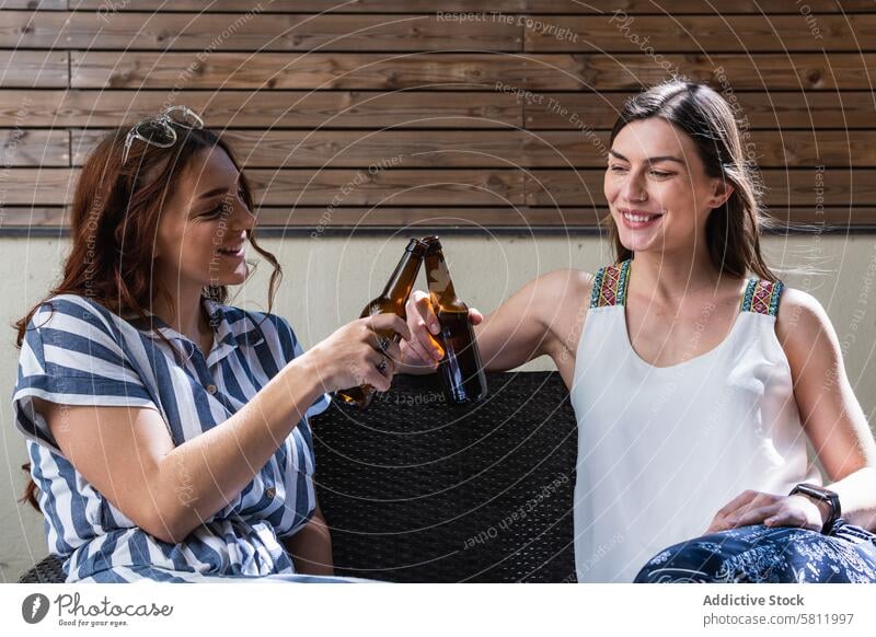 Fröhliche Freundinnen mit Bier am Wochenende auf dem Sofa jubelt interagieren heiter Zeit verbringen Lifestyle Porträt Frauen Lächeln Kälte Alkohol trinken