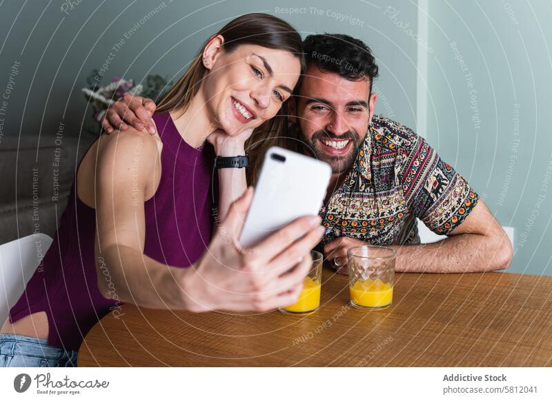Lächelndes Paar macht Selfie in der Küche Smartphone Glück Zahnfarbenes Lächeln Umarmung Zusammensein Freund Selbstportrait Gedächtnis fotografieren Telefon
