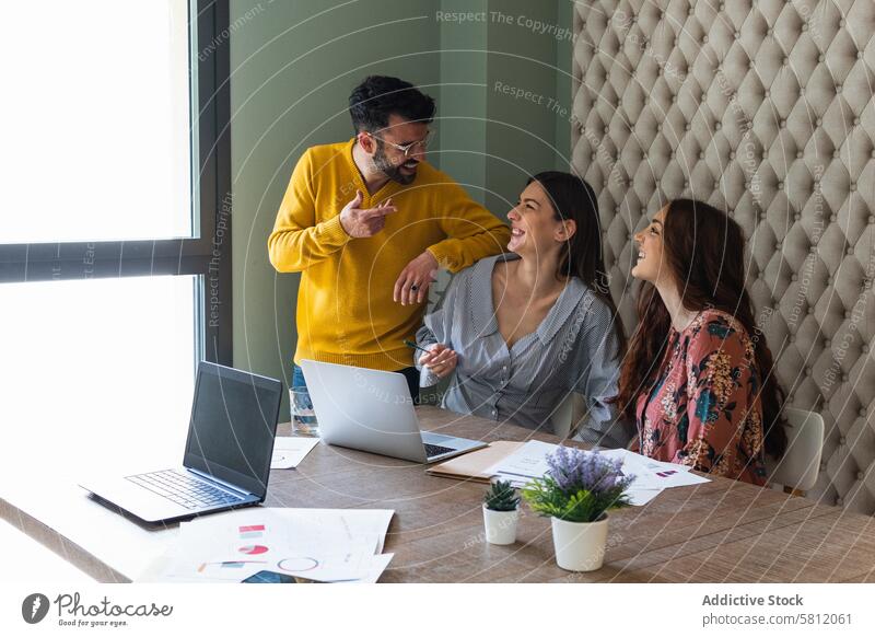 Fröhliche Kollegen besprechen ein Projekt in einem modernen Arbeitsraum heiter diskutieren Büro Menschengruppe Lachen Teamwork Mitarbeiterin Kommunizieren