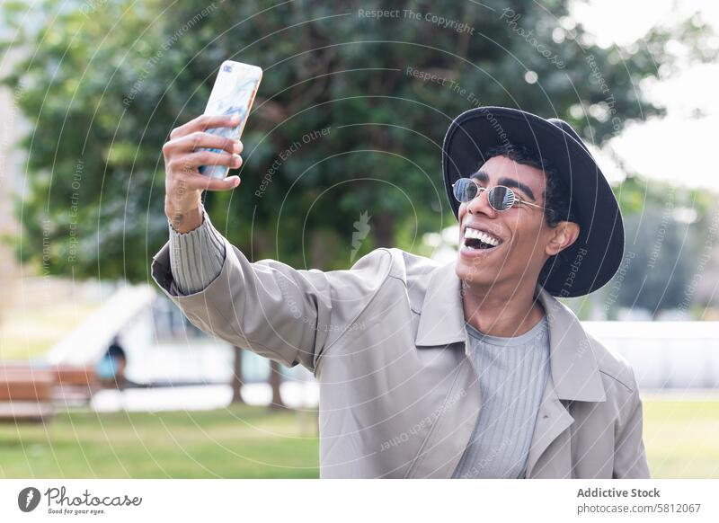 Stilvoller ethnischer Mann, der ein Selfie mit seinem Smartphone macht trendy benutzend Glück Hipster positiv cool männlich Lächeln Selbstportrait stehen