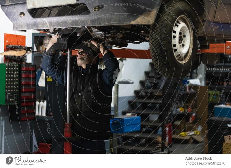 Mechaniker beim Entfernen von Fahrzeugteilen mit einer Taschenlampe während der Arbeit in einer Autowerkstatt Mann Dienst PKW Fackel Garage Reparatur manuell