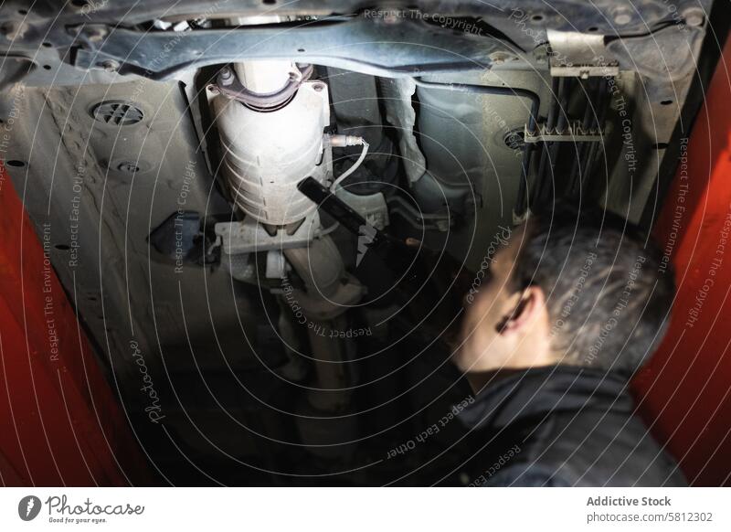 Anonymer Mechaniker, der die Auspuffanlage eines Autos in der Werkstatt untersucht Mann prüfen Dienst Garage Flugzeugwartung Fahrzeug Diagnostik inspizieren