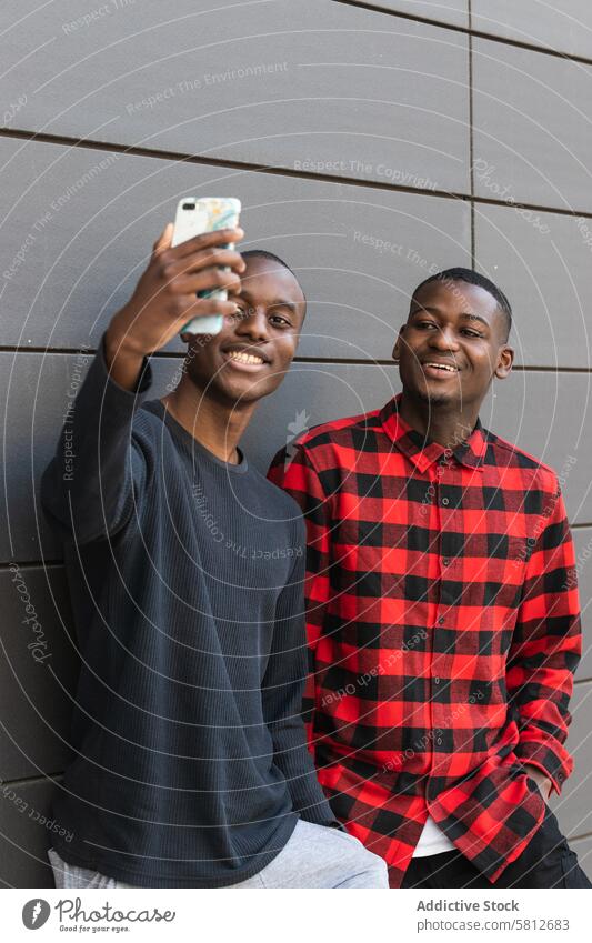 Schwarz lächelnde Männer, die ein Selfie mit ihrem Smartphone machen benutzend Freund Zusammensein heiter froh positiv Freundschaft männlich Glück Funktelefon
