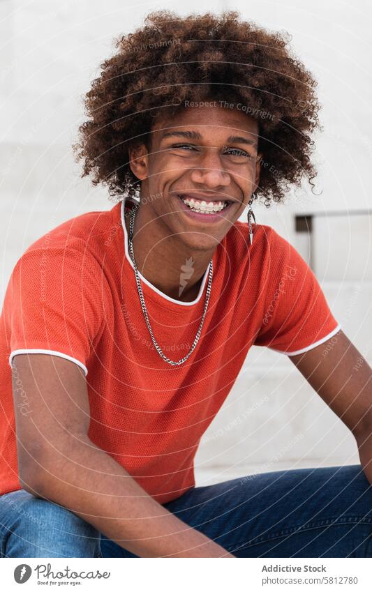 Positiver junger Schwarzer, der in die Kamera lächelt, während er auf der Straße chillt Mann Kälte Lächeln Stil charismatisch Persönlichkeit tausendjährig urban