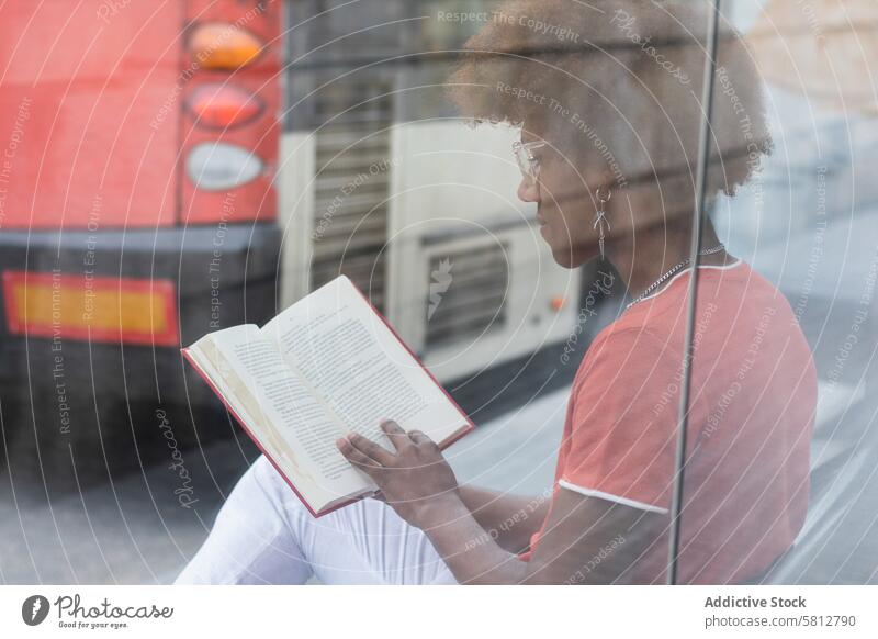 Stilvoller junger Schwarzer, der an der Bushaltestelle ein Buch liest Mann lesen Konzentration Literatur Leseratte Windstille sich[Akk] entspannen interessant