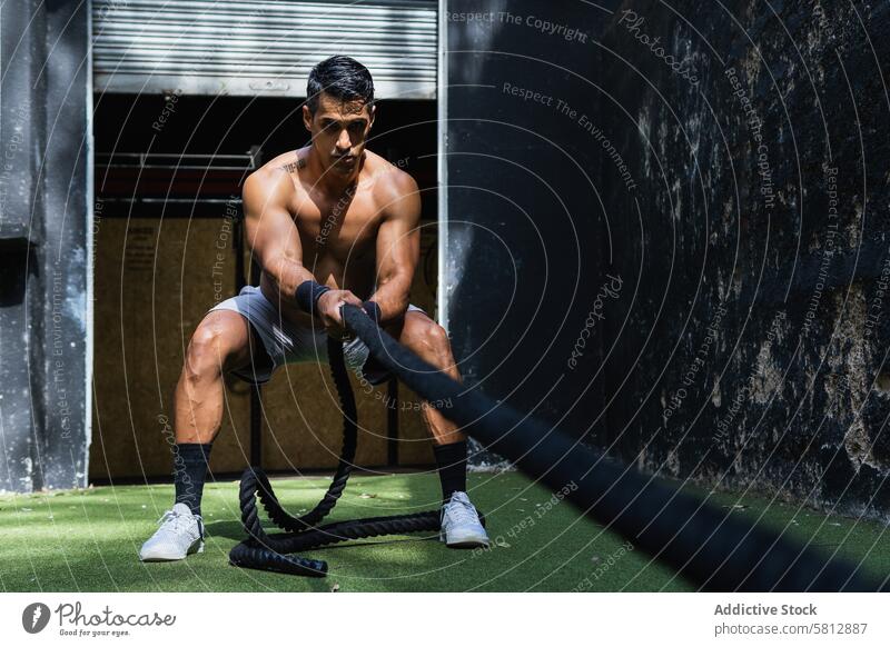 Muskulöser hispanischer Sportler, der einen Schlitten zieht Gewicht ziehen Kraftdreikampf Training Fitnessstudio Übung sportlich Gesunder Lebensstil