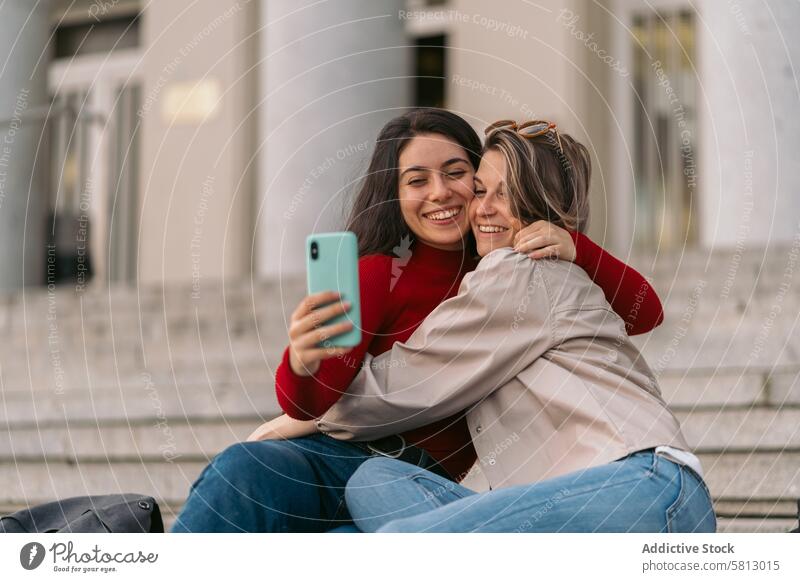 Zwei Studentinnen machen lächelnd ein Selfie auf der Treppe des Colleges. Lifestyle Fröhlichkeit zwei Frau Frauen Mädchen jung Urlaub Freunde Schüler Jugend
