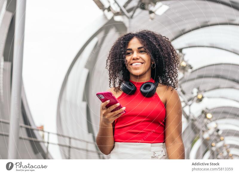 Porträt eines Mädchens mit Afro-Haar genießen in der Stadt mit Smartphone Afroamerikaner Sommer Jugend Mitteilung Freude lachen Fröhlichkeit Freizeit Erholung