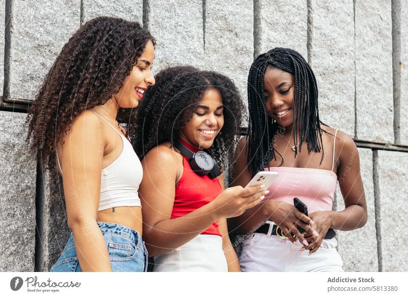 Vernetzte junge Menschen: Freundinnen nutzen Smartphones in der Stadt Afroamerikaner Sommer Freunde Vielfalt Jugend Mitteilung Freude lachen Fröhlichkeit