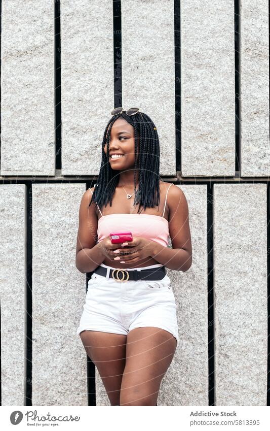 Porträt einer schwarzen jungen Frau, die sich mit ihrem Smartphone in der Stadt vergnügt Afroamerikaner Sommer Jugend Mitteilung Freude lachen Fröhlichkeit
