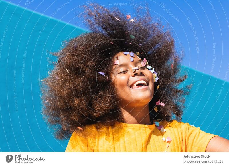 Entzücktes schwarzes Mädchen hat Spaß mit Konfetti Kind Glück farbenfroh Spaß haben krause Haare Afro-Look sorgenfrei Sommer sonnig Teenager Afroamerikaner