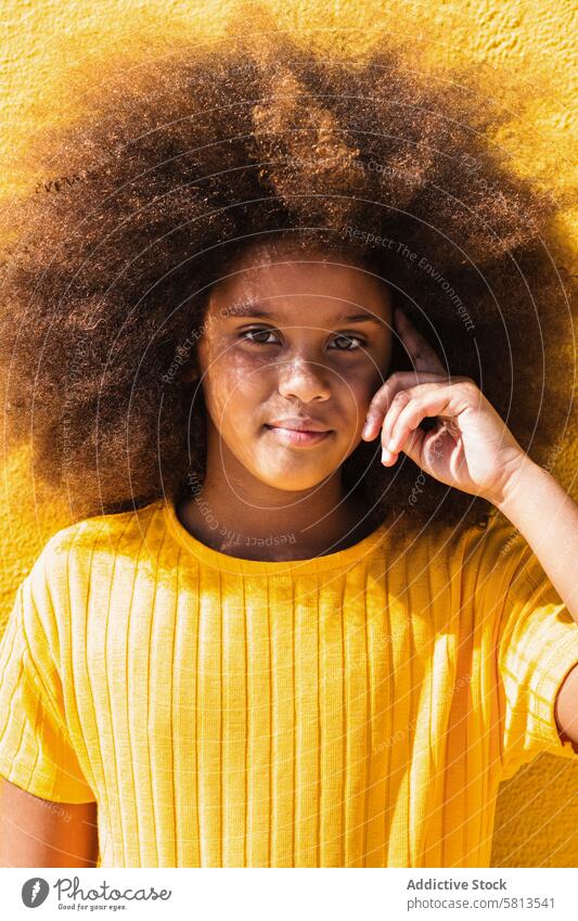Ethnisches Mädchen mit Afrofrisur schaut in die Kamera Afro-Look Frisur krause Haare Teenager Porträt Kind Menschliches Gesicht gelb Afroamerikaner schwarz