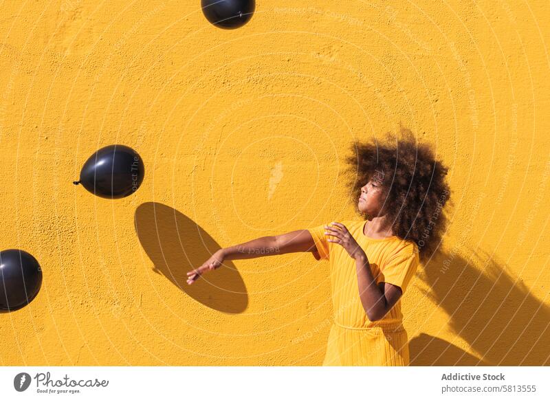 Glückliches schwarzes Mädchen spielt mit Luftballons spielen gelb Afro-Look krause Haare farbenfroh Farbe Spaß haben lebhaft Kind Teenager Frisur ethnisch