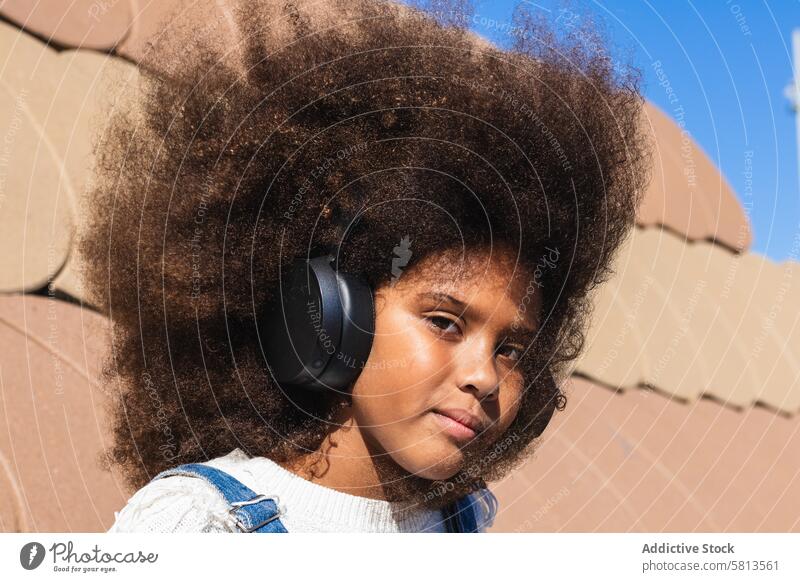 Afroamerikanisches Mädchen, das mit Kopfhörern Musik hört zuhören Afro-Look Teenager Hipster Drahtlos Kind krause Haare schwarz Afroamerikaner ethnisch Frau