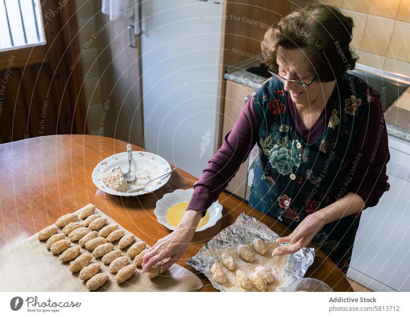 Ältere Frau bereitet zu Hause viele handgemachte Kroketten zu Draufsicht Glück gealtert vorbereitend Lose handgefertigt heimwärts kulinarisch selbstgemacht