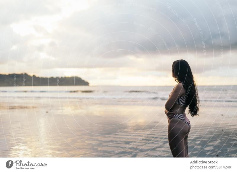 Junge Frau, die am Strand stehend den Sonnenuntergang beobachtet jung MEER Sommer Lifestyle Glück reisen schön Meer Natur Urlaub Menschen Himmel Fröhlichkeit