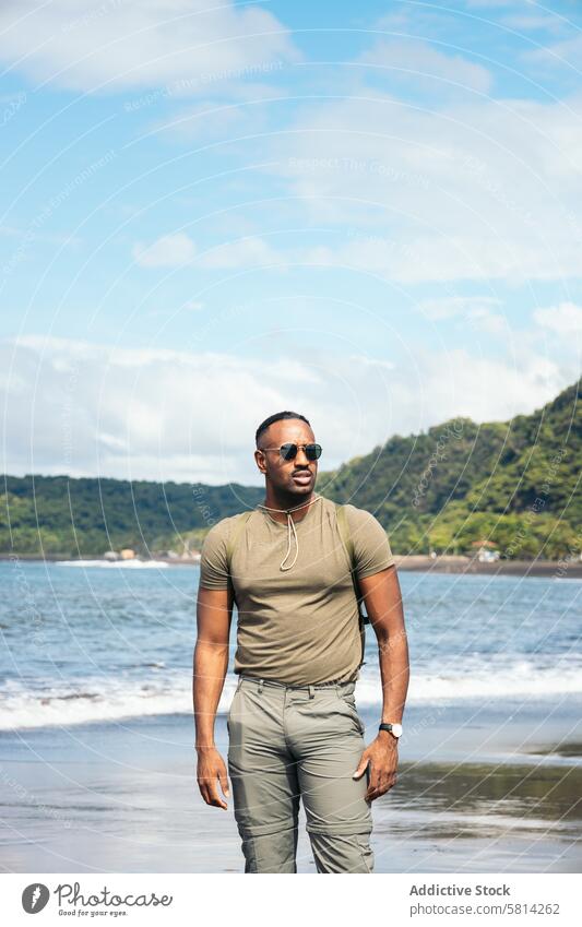 Afroamerikanischer Mann mit Kleidung am Strand schwarz Sonnenbrille männlich jung Hintergrund Typ stylisch Urlaub Glück reisen Porträt Lifestyle cool