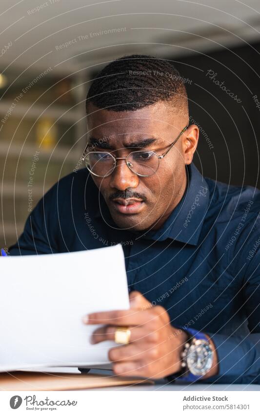 Afroamerikanischer Mann, der in der Nähe eines Laptops im Büro in einen Notizblock schreibt zur Kenntnis nehmen Notebook Netbook Tisch Schriftstück