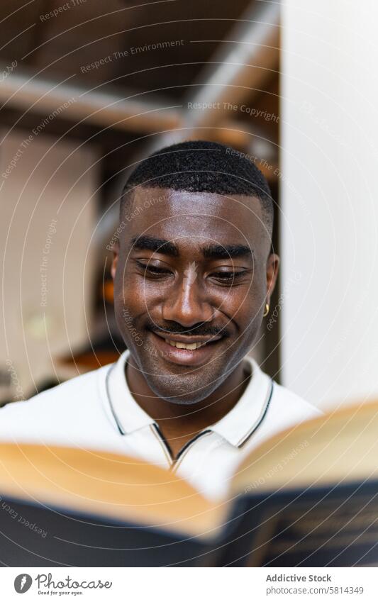 Männlicher Afroamerikaner liest ein Buch in der Cafeteria Mann lesen Kantine allein Hobby Roman Café schwarz männlich Erwachsener Etage Konzentration Wissen